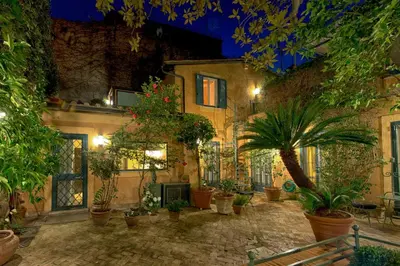 a courtyard with potted plants in a building at night at Buonanotte Garibaldi in Rome