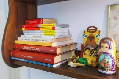a stack of books sitting on a shelf with a doll at All'Ombra Del Cupolone Guest House in Rome