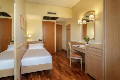 a room with two beds and a desk and a sink at Hotel Santa Costanza by OMNIA hotels in Rome