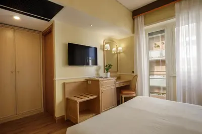 a bedroom with a bed and a desk with a television at Hotel Santa Costanza by OMNIA hotels in Rome