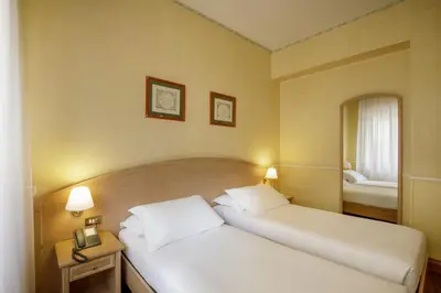 a hotel room with two beds and a mirror at Hotel Santa Costanza by OMNIA hotels in Rome