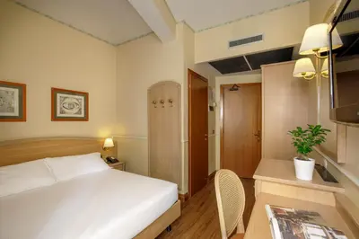 a bedroom with a bed and a table and a chair at Hotel Santa Costanza by OMNIA hotels in Rome