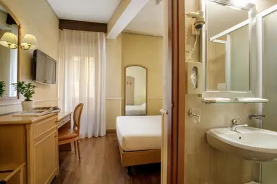 a bathroom with a sink and a bed and a mirror at Hotel Santa Costanza by OMNIA hotels in Rome