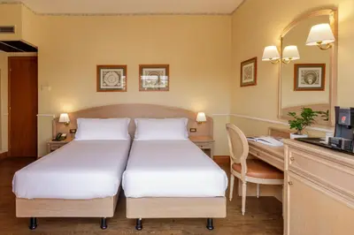 a hotel room with two beds and a desk at Hotel Santa Costanza by OMNIA hotels in Rome