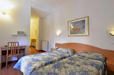 a hotel room with two beds and a desk at Hotel Tirreno in Rome