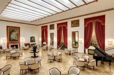 a room with a piano and tables and chairs at Hotel Quirinale in Rome