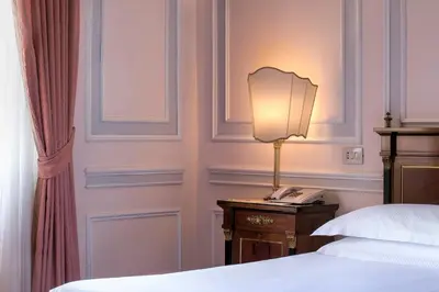 a bedroom with a bed and a lamp on a table at Hotel Quirinale in Rome