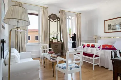 a woman standing in a bedroom looking out the window at Grand Hotel Plaza in Rome