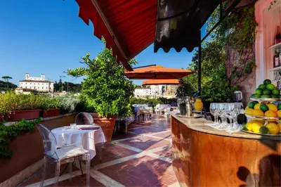 a patio with tables and chairs and an umbrella at Grand Hotel Plaza in Rome