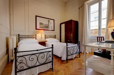 a bedroom with two beds and a table and a window at Grand Hotel Plaza in Rome