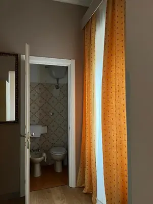 a bathroom with an orange shower curtain and a toilet at Hotel King in Rome