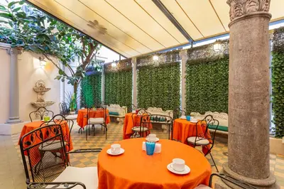 a restaurant with orange tables and chairs and a green hedge at Hotel Medici in Rome
