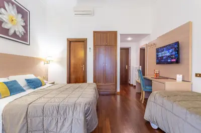 a hotel room with two beds and a desk at Hotel Medici in Rome