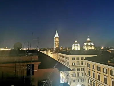 a view of a city at night with a clock tower at Hotel Palladium Palace in Rome