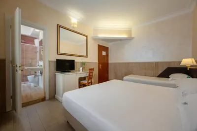 a hotel room with a white bed and a bathroom at Hotel Palladium Palace in Rome