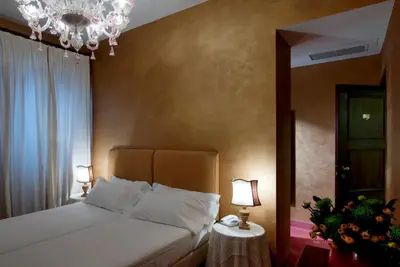 a bedroom with a bed with two lamps and a chandelier at Hotel Columbia in Rome