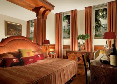 a bedroom with a bed and a table and windows at Hotel Raphaël - Relais & Châteaux in Rome
