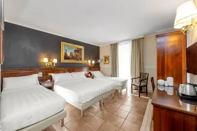 a hotel room with two beds and a table at Hotel Des Artistes Roma in Rome