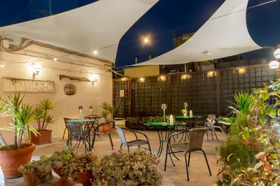 a patio with tables and chairs and potted plants at Hotel Des Artistes Roma in Rome
