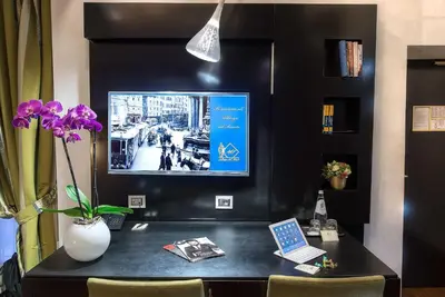 a desk with a tv and a vase with purple flowers at Albergo del Senato in Rome