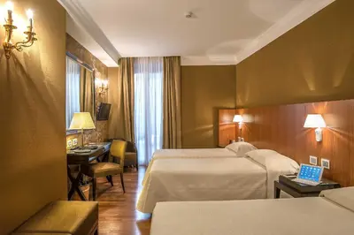 a hotel room with two beds and a desk at Albergo del Senato in Rome