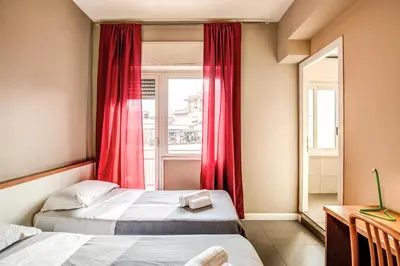 a bedroom with two beds and a window with red curtains at City Guest House in Rome