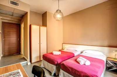two beds in a hotel room with pink sheets at City Guest House in Rome