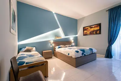 two beds in a bedroom with blue walls at Giulio Cesare Imperatore in Rome
