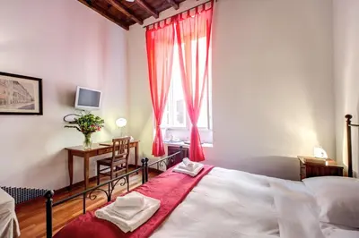 a bedroom with a bed and a desk and a window at Nova Domizia in Rome