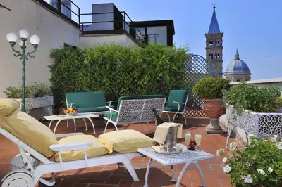 a patio with chairs and tables and a clock tower at Hotel Mecenate Palace in Rome
