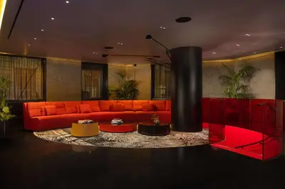 a living room with a red couch and a fireplace at art'otel Rome Piazza Sallustio in Rome