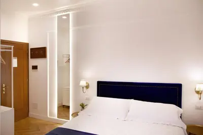 a bedroom with a white bed with a blue headboard at Hotel Silva in Rome