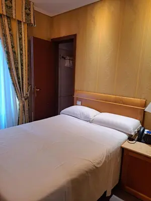 a bedroom with a large white bed and a telephone at Hotel dei Quiriti in Rome