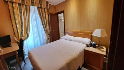 a bedroom with a bed and a desk with a lamp at Hotel dei Quiriti in Rome