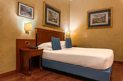 a bedroom with a large bed with a nightstand and two pictures at Hotel Miami in Rome