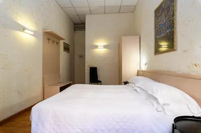 a bedroom with a white bed and a chair at Hotel Julia Trevi - Spagna in Rome