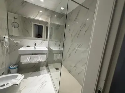a white bathroom with a shower and a sink at Hotel Gabriella in Rome