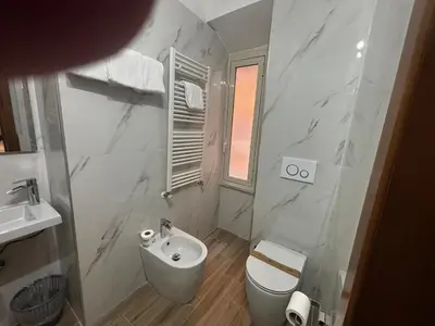 a white bathroom with a toilet and a sink at Hotel Gabriella in Rome