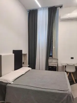a bedroom with a bed and a desk and a window at Hotel Viennese in Rome