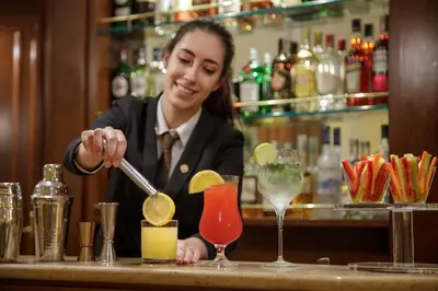 a woman preparing a drink at a bar at Donna Laura Palace by OMNIA hotels in Rome