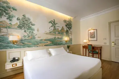 a bedroom with a white bed and a painting on the wall at Donna Laura Palace by OMNIA hotels in Rome