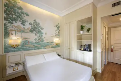 a bedroom with a white bed and a painting on the wall at Donna Laura Palace by OMNIA hotels in Rome