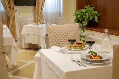 a table with a plate of food and glasses of wine at Donna Laura Palace by OMNIA hotels in Rome