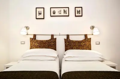 two beds in a bedroom with three pictures on the wall at B&B Arco Del Lauro in Rome