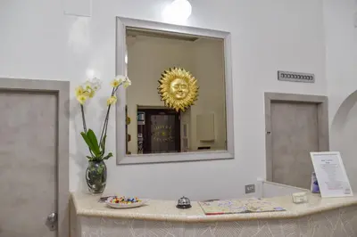 a counter with a vase of flowers and a mirror at Hotel Sol Levante in Rome