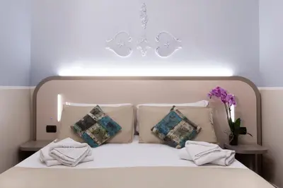 a bedroom with a white bed with pillows and a chandelier at Hotel Grifo in Rome