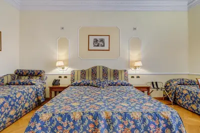 a bedroom with a bed and two chairs at Hotel Cellini in Rome