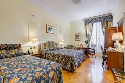 a hotel room with two beds and a table at Hotel Cellini in Rome
