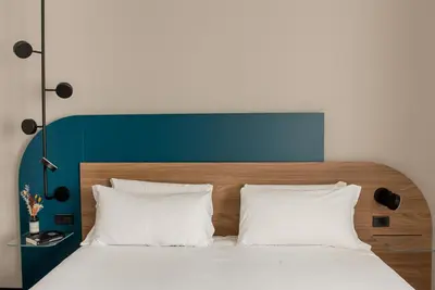 a bed with a blue headboard and two white pillows at Belstay Roma Aurelia in Rome