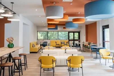 a waiting room with tables and yellow chairs at Belstay Roma Aurelia in Rome